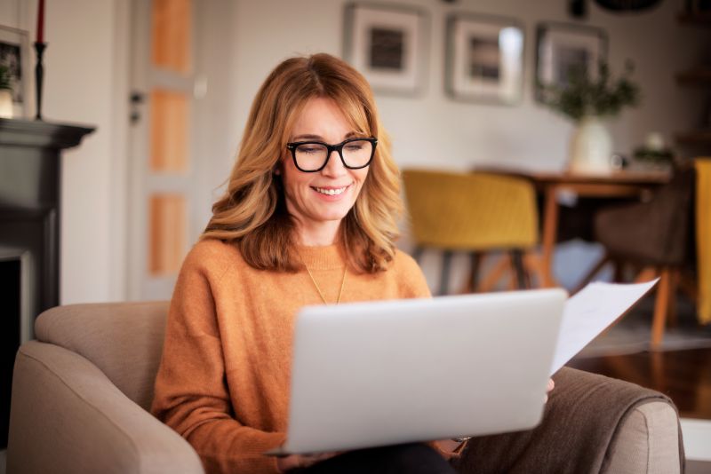 A woman sitting on a coach with a laptop.